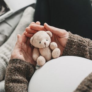 Woman pregnant belly with little teddy toy bear. Concept image with symbol of many meanings for expectant mother during pregnancy and her unborn baby.
