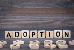 Adoption word written on wood block. Dark wood background with texture