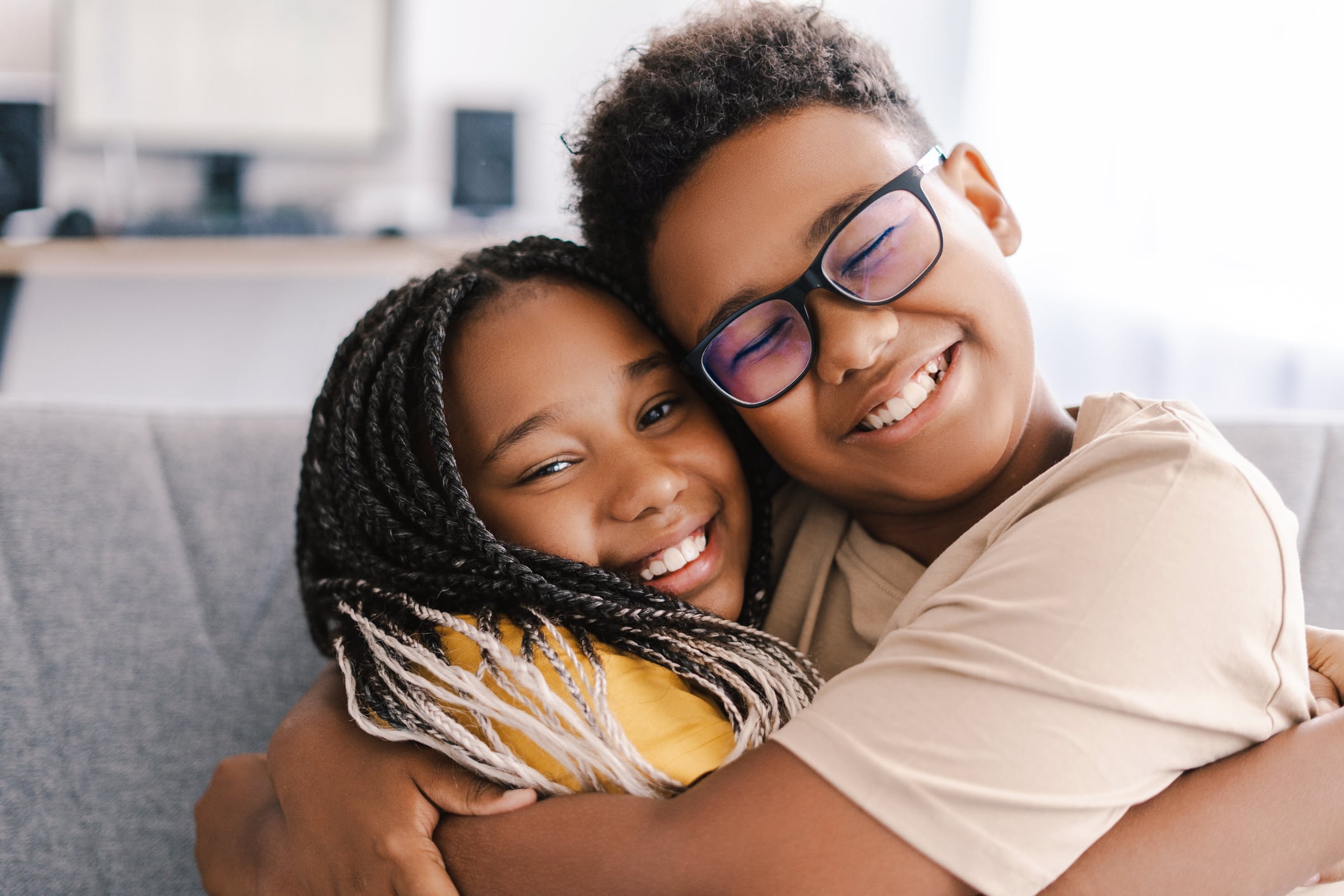 Two happy children embracing on the sofa at home